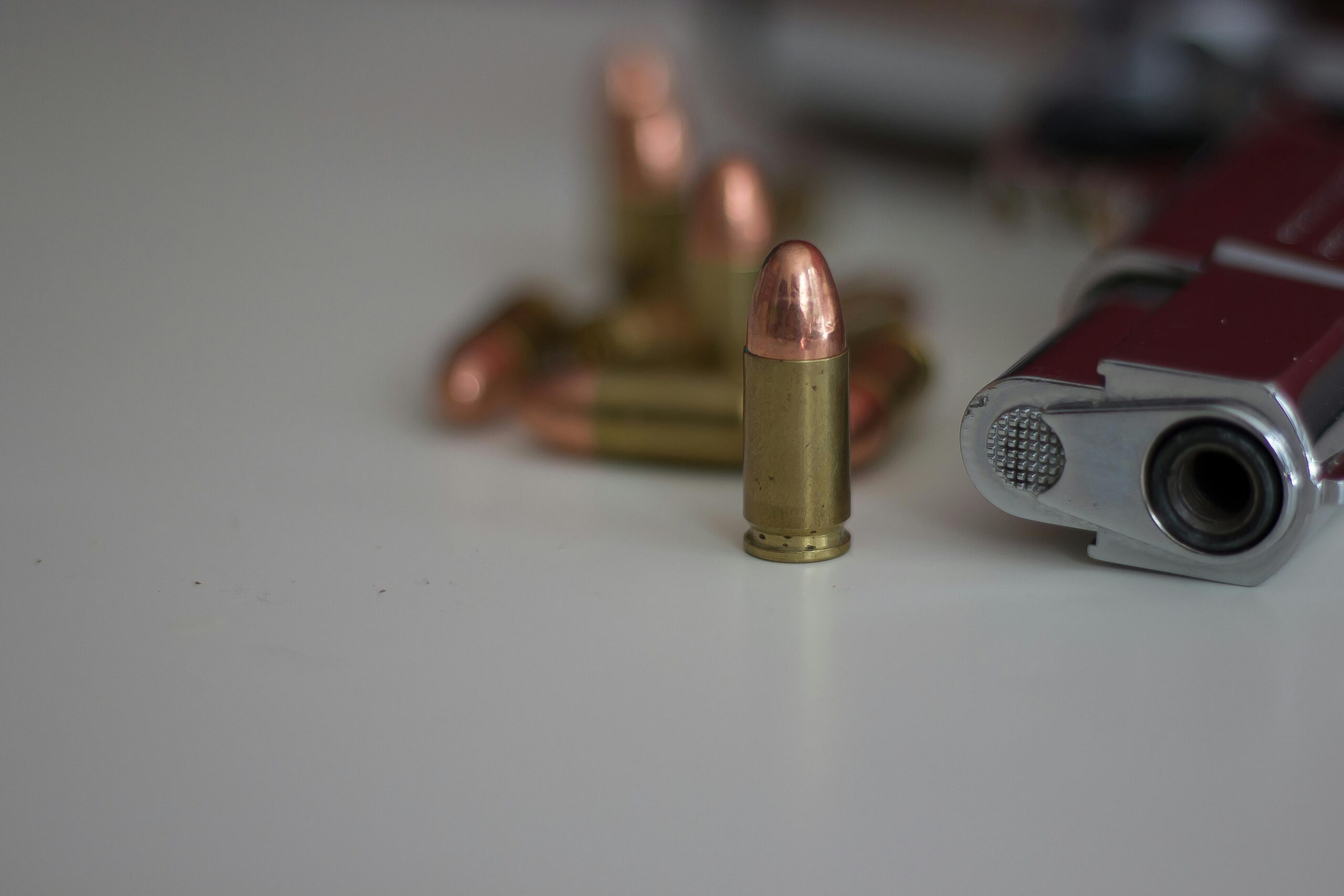 A detailed image of a handgun and multiple bullets on a white background, showing focus on firearm elements.